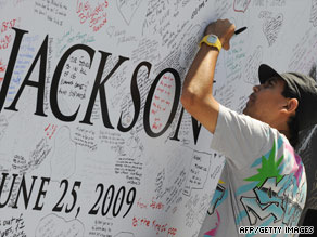 A fan signs a Michael Jackson poster covered in messages outside the Staples Center in Los Angeles Monday.
