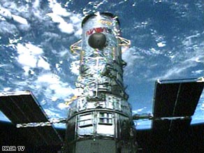 The Hubble Space Telescope waits in the payload bay of the shuttle Atlantis for the start of the first spacewalk.