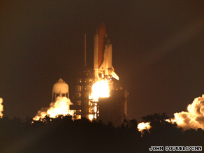 Space shuttle Discovery lights up the nighttime sky during its journey to the international space station.