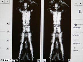 A TSA employee, shown from the back, as he stands in an airport whole-body imaging machine.