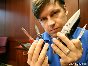 An Atlanta TSA officer holds up some prohibited knives surrendered by passengers over the last month.
