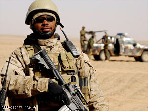 A U.S. soldier stands guard as policemen destroy poppy fields in Nadi Ali district, February 5, 2009.