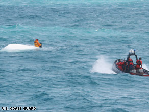 Nick Schuyler clings to an overturned boat Monday in this Coast Guard photo.