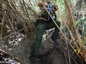 A Border Patrol agent moves through dense cane on the banks of the Rio Grande near Laredo, Texas, last year.