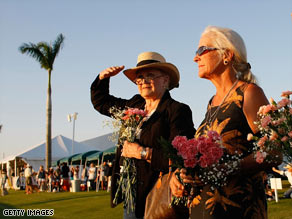 A groom walks a horse past flowers left for the polo ponies at the International Polo Club Palm Beach.