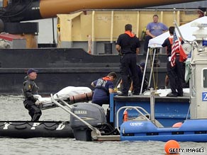 Divers unload a body from their raft onto a police boat Sunday. Nine people are believed dead in the crash.