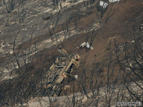 A firefighter speeds away from a dangerous wall of flames Sunday in Acton.