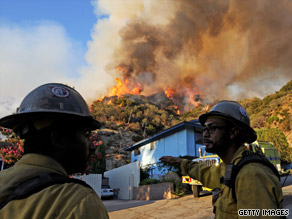 Firefighters stand by Monday as a wall of flames from a backfire light up a hillside in La Crescenta, California.