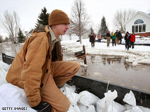 Kevin Hard rides in a trailer loaded with sandbags Wednesday in Oxbow, North Dakota.
