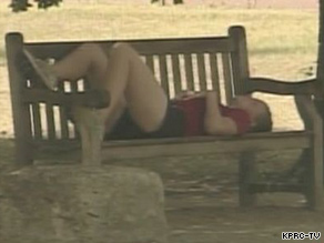 A woman tries to beat Houston's record heat by lying on a bench in the shade.