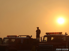 Residents stand on their roof Tuesday as a wildfire burns near their home in Glendale, California.