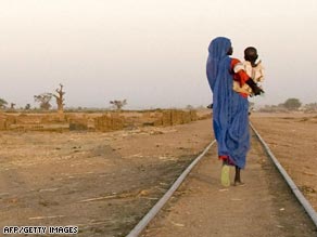 A woman left homeless by conflict in Darfur walks along railway tracks.