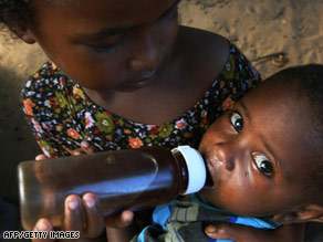 A young girl feeds her baby brother at a refugee camp  on the outskirts of Mogadishu, Somalia.