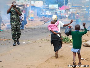 A man tries to put out a fire set in the streets of the Kasubi suburb Friday during sectarian violence.