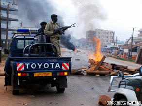 Residents of Kasubi raise their hands as they walk past riot police Friday.