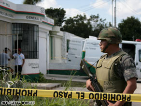 A soldier guards the forensics office where the body of a slain former general was taken in Cancun, Mexico.