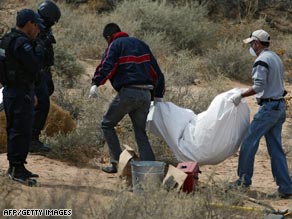 Police look on as one of the nine bodies found in a common grave near Ciudad Juarez, Mexico, is removed.