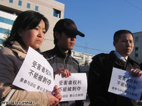 Victims' relatives outside a court hold banners that read "cannot deprive the victims' rights."