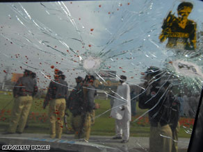 Police gather beside the wreckage of a police van in Lahore, Pakistan, following Tuesday's attack.