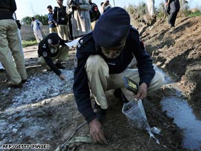 Policemen collect evidence after an explosion on security forces outside Peshawar, Pakistan, Saturday.