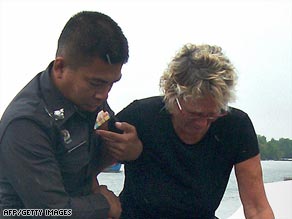 Linda Robertson is helped by Thai police after her husband was allegedly murdered by pirates.