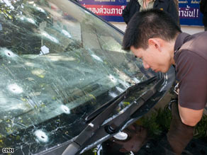 Thai troops pass a smoldering bus in central Bangkok.