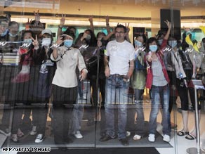 Quarantined guests and hotel employees wave through the glass of the main entrance of Hong Kong's Metro Park Hotel.