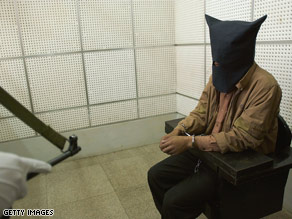 A Chinese policeman guards an illegal trafficker at a detention cell in Kunming, Yunnan Province, China.