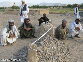 Villagers sit near the graves of victims of recent airstrikes in Garni, in western Farah province.