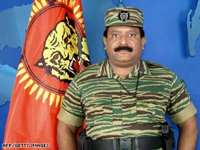 In this picture taken 27 November 2003, Velupillai Prabhakaran stands next to an LTTE flag.