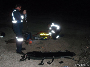 Air ambulance workers attend to a man buried in sand following a helicopter crash.