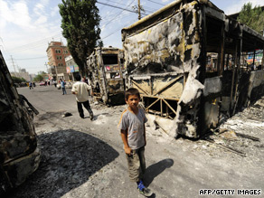 A boy stands in front of the burned wreckage of a bus in Urumqi, July 6, 2009.