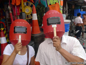 A couple try out welding screens bought from a hardware store to view the eclipse in Beijing on Tuesday.