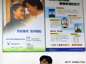 A man sits beneath fertility advertising in Beijing in 2005.