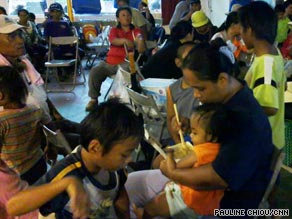 Survivors and relatives wait for more rescued villagers to arrive by helicopter at the Nei Pu school.