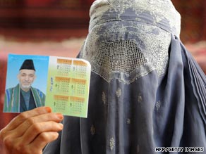 An Afghan woman in a burqa veil holds up a photograph of President Hamid Karzai.