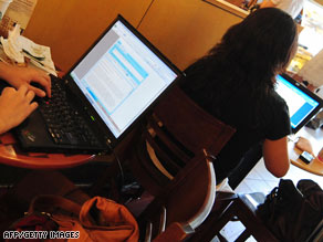 People sit at a wireless cafe in Beijing, using their laptop computers.