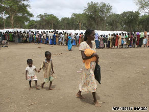 A Tamil mother walks with her children as civilians wait for food at the Manik Farm refugee camp, May 26, 2009.