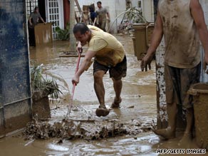 Residents remove mud from a home Monday as waters recede in Marikina City, suburban Manila.