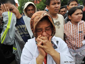 A resident stands next to building that collapsed onto a car in Padang, Indonesia, on Wednesday.