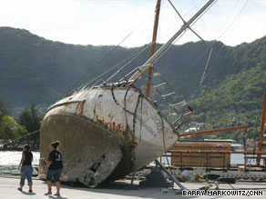 Red Cross workers walk past a boat last month that was uplifted by the tsunami at Pago Pago Harbor, American Samoa.