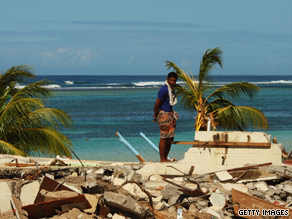 Red Cross workers walk past a boat uplifted by the tsunami at Pago Pago Harbor.