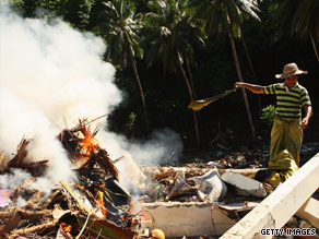 A man throws rubble onto a fire burning on what used to be his parents' home in Samoa.