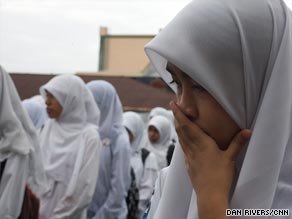 Students inspect their damaged classroom, with tables broken and shards littering the ground.