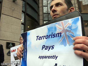 Protesters hold signs outside the Europa Hotel in Belfast before the presentation of the report.