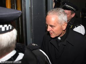 Richard Williamson is surrounded by police as he arrives in London on Wednesday.