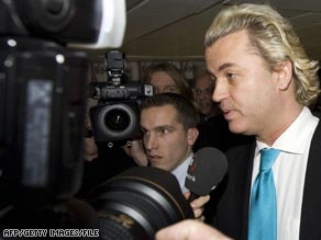 Wilders (right) tries to enter the UK at Heathrow Airport surrounded by reporters.