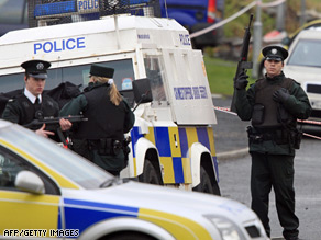 Armed police guard a grey Skoda vehicle, right in background, in which a policeman was killed in Craigavon.