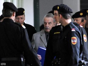 Josef Fritzl is seen without his face covered and surrounded by security guards Tuesday.