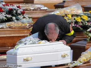 A rescue worker Friday kisses the coffin of a child killed by this week's earthquake in central Italy.